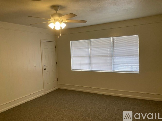 A room with a ceiling fan and a window with blinds.