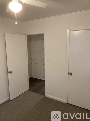 A room with a carpeted floor and two doors.