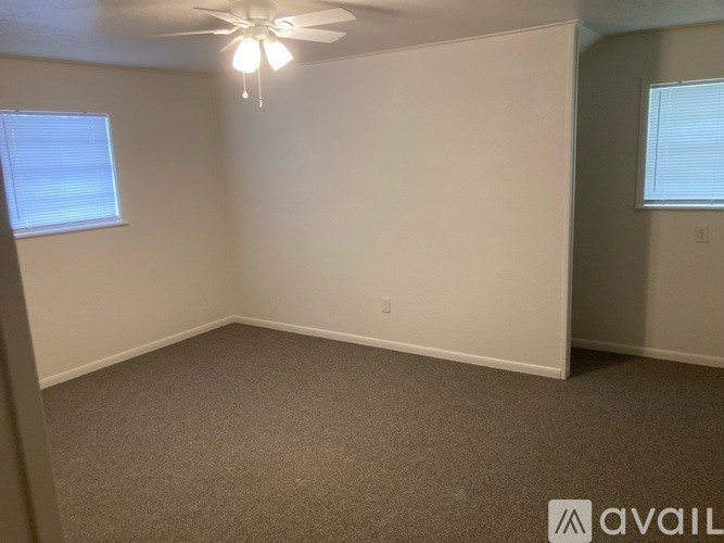 A room with a ceiling fan and carpeted floor.