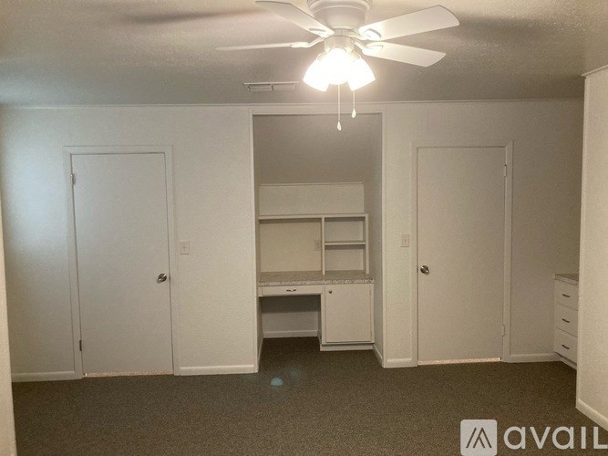 A room with a ceiling fan and a desk with drawers.