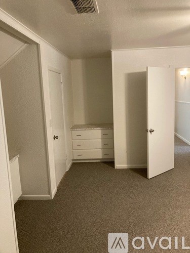A room with a carpeted floor and a dresser with a mirror.