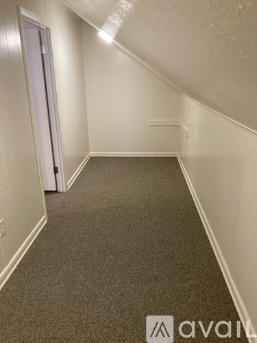 A hallway with a carpeted floor and white walls.