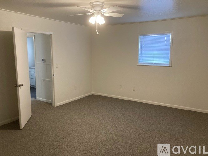 A room with a ceiling fan and a window with blinds.