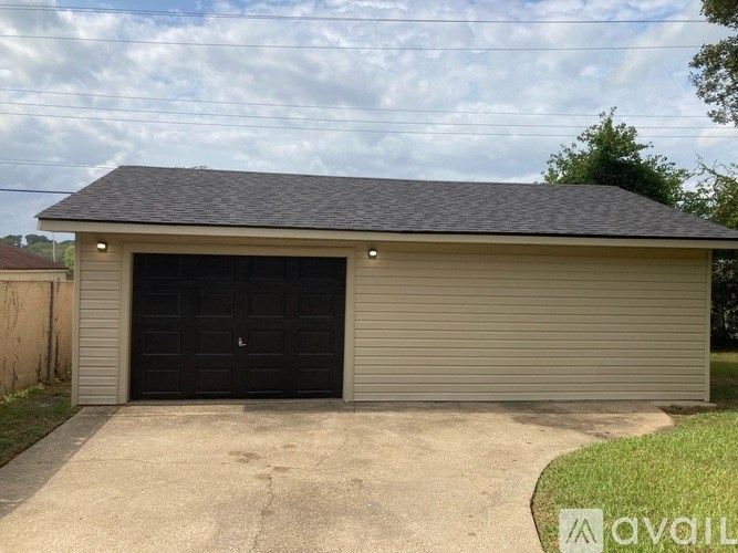 A two-car garage with a black door is situated in a driveway.