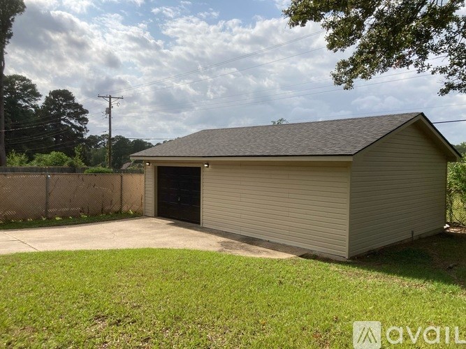 A detached garage with a closed grey door is situated in a grassy area.