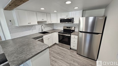 A modern kitchen with a stainless steel refrigerator and a marble countertop.