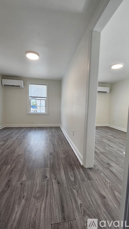A room with wooden flooring and a window.