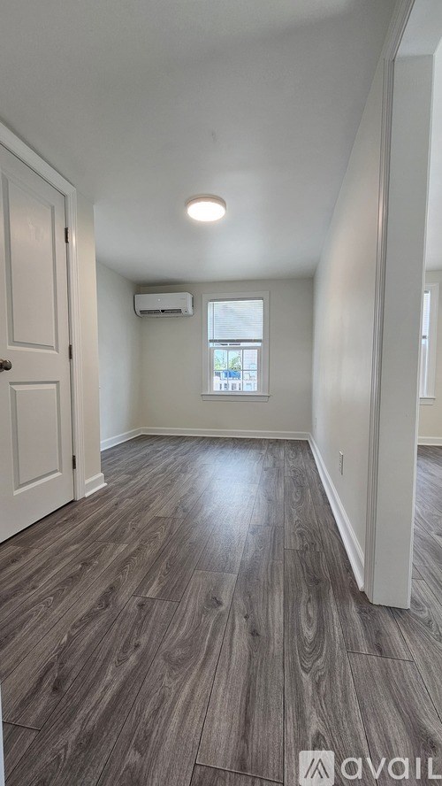 A long hallway with wood floors and white walls.