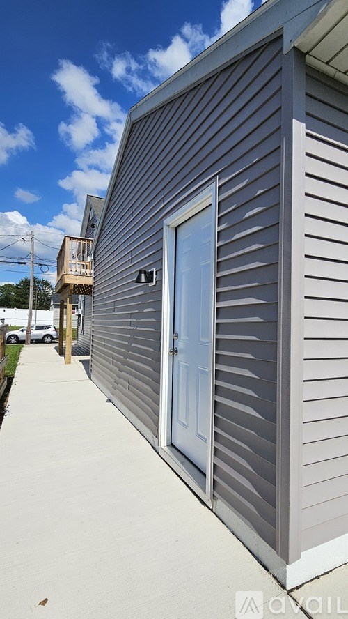 A grey house with a blue door and a window.