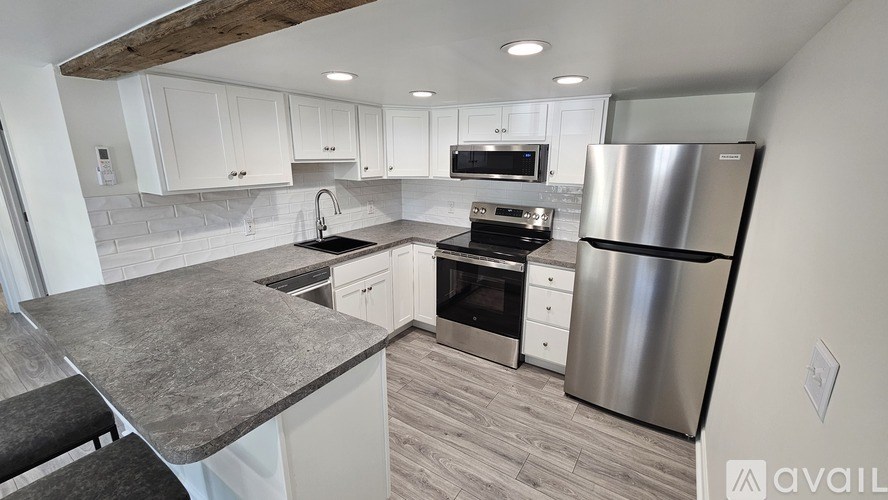 A modern kitchen with a stainless steel refrigerator and a granite countertop.