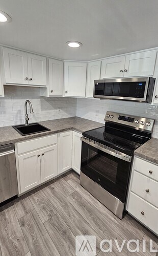 A kitchen with white cabinets and a wood floor.