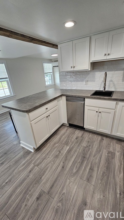 A kitchen with white cabinets and a wooden floor.