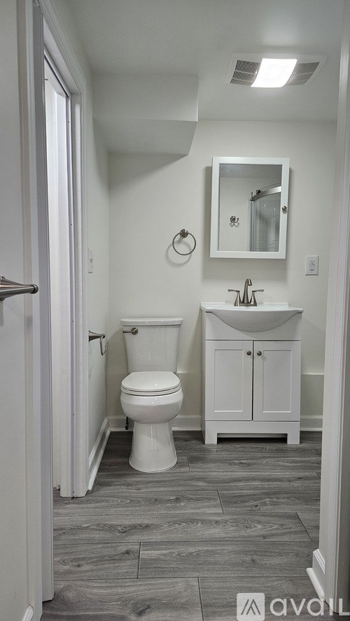 A bathroom with a toilet, sink, and mirror.