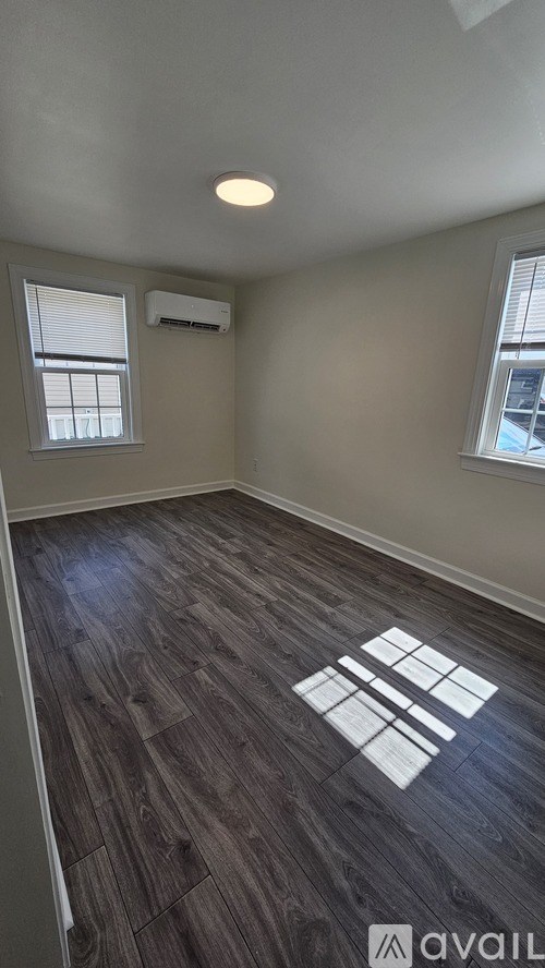 A room with wooden flooring and a window with blinds.