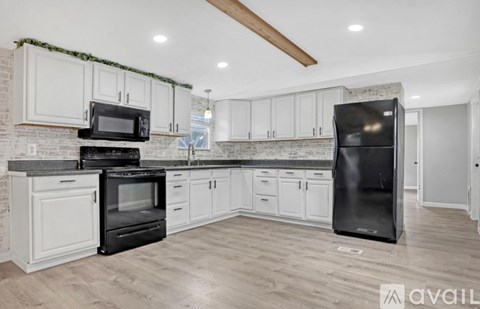 A kitchen with white cabinets and a black fridge.
