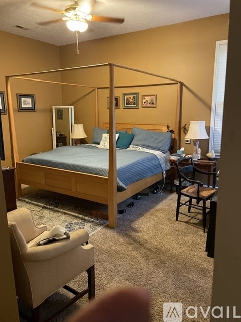 A bedroom with a four poster bed and a chair.