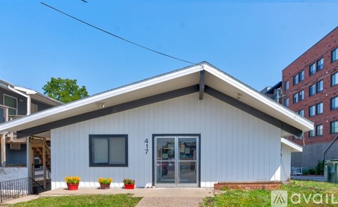 A white building with a black door and windows is numbered 47.