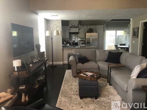 A living room with a grey couch and a television on the wall.