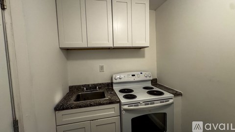 A kitchen with white cabinets and a stove top oven.