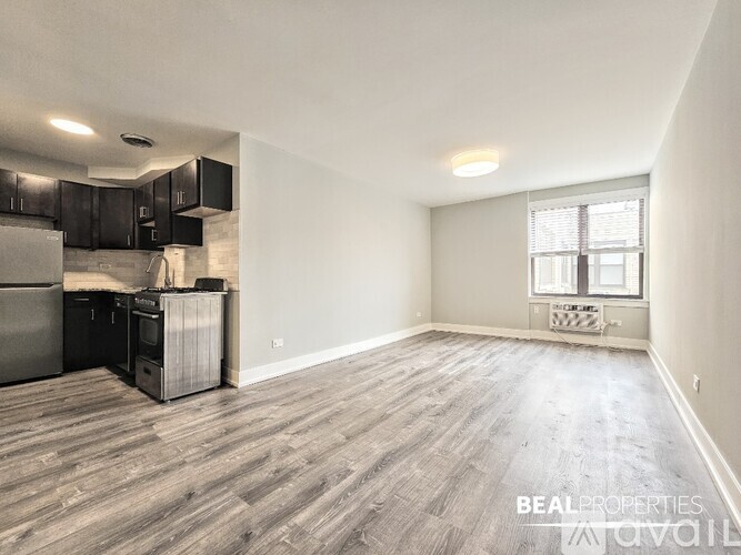 A spacious room with wood flooring and a window with blinds.