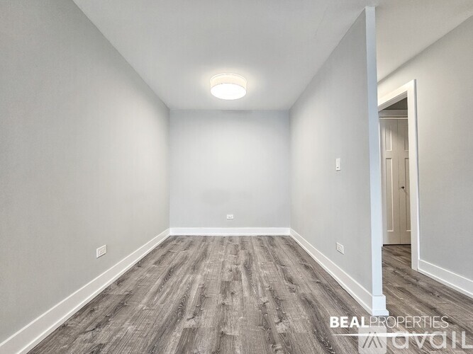 A spacious room with wooden flooring and white walls.
