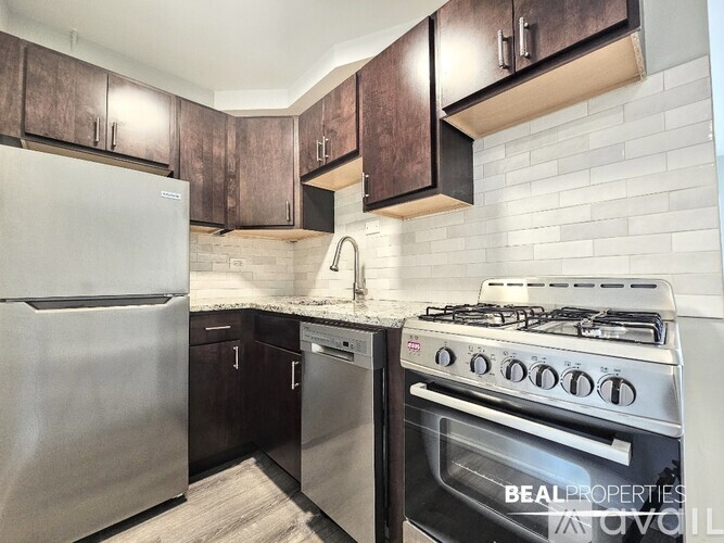 A modern kitchen with a stainless steel refrigerator and a stove with a white tile backsplash.