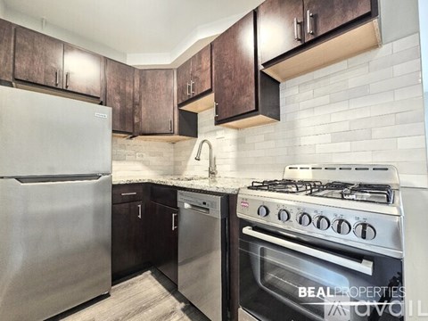 A modern kitchen with a stainless steel refrigerator and a stove with a white tile backsplash.
