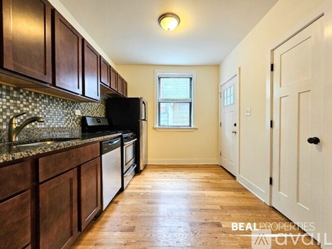 A kitchen with wooden cabinets and a black refrigerator.