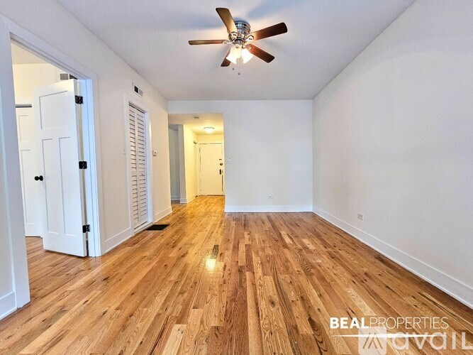 A spacious room with wooden flooring and a ceiling fan.