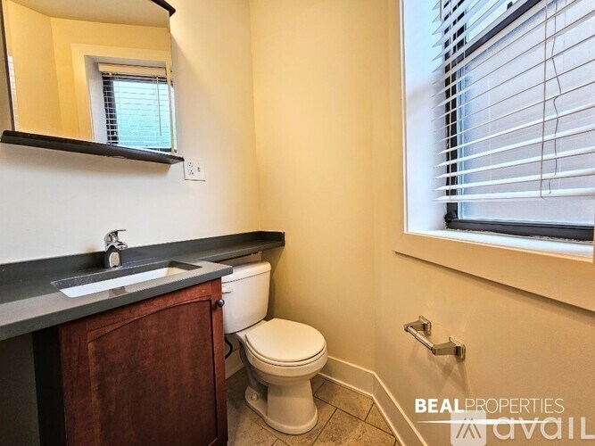 A bathroom with a toilet, sink, and mirror.