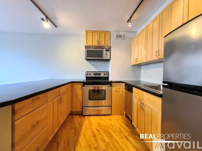A kitchen with wooden cabinets and stainless steel appliances is available for rent.