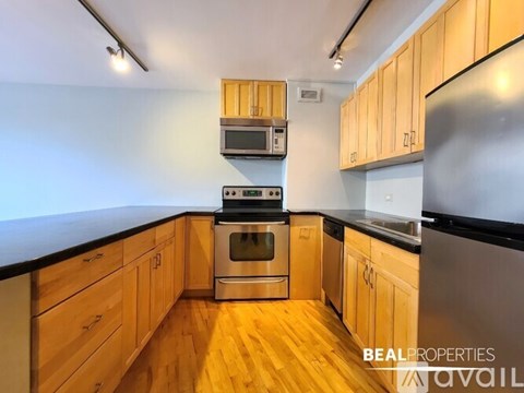 A kitchen with wooden cabinets and stainless steel appliances is available for rent.