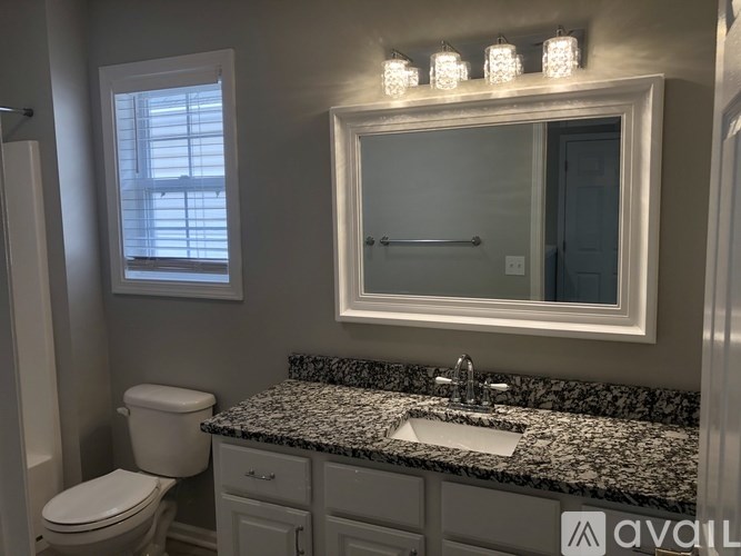 A bathroom with granite countertop and a large mirror.