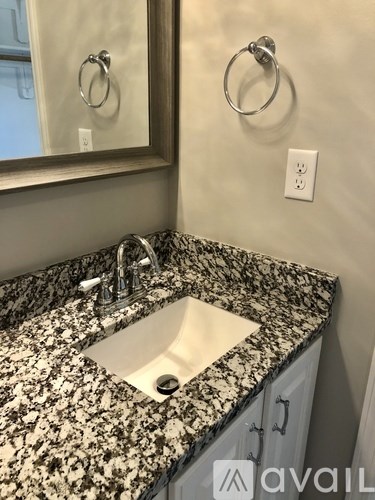 A bathroom sink with a granite countertop and a mirror above it.
