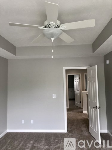 A room with a ceiling fan and a doorway leading to another room.
