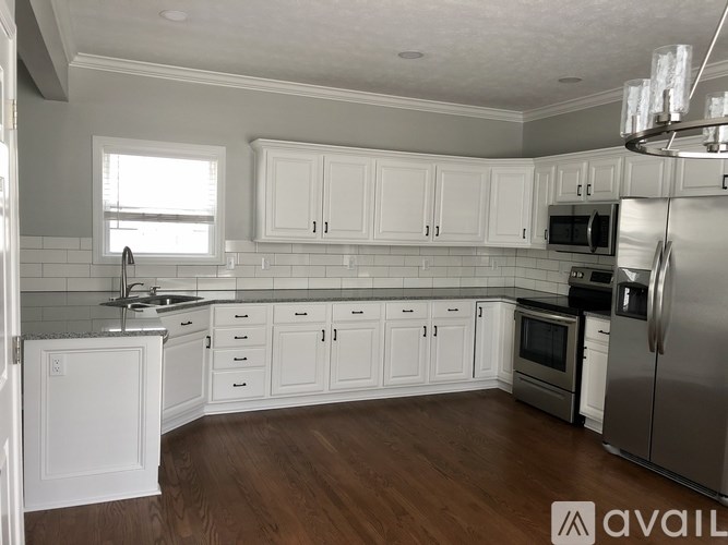 A kitchen with white cabinets and a wooden floor.