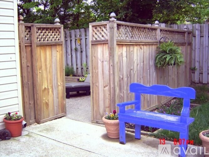 A blue bench sits in front of a wooden fence and gate.