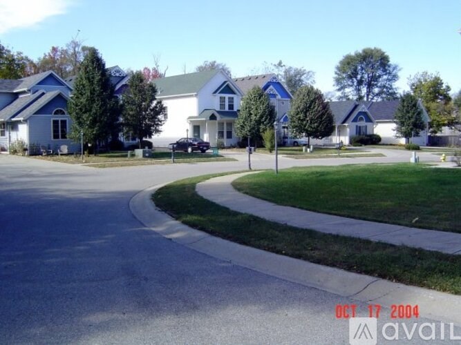 A residential street with houses on both sides and a car parked on the street.