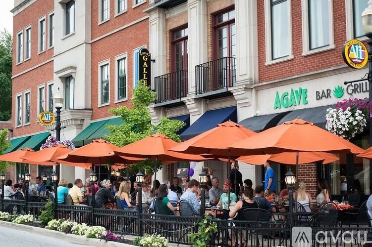 A group of people are sitting at tables under orange umbrellas outside of a restaurant.
