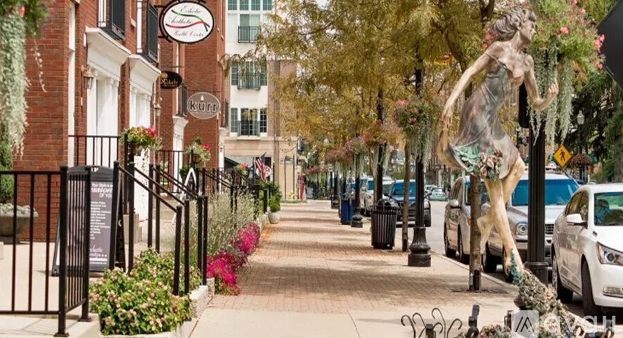 A statue of a person holding a plant is in the middle of a street.