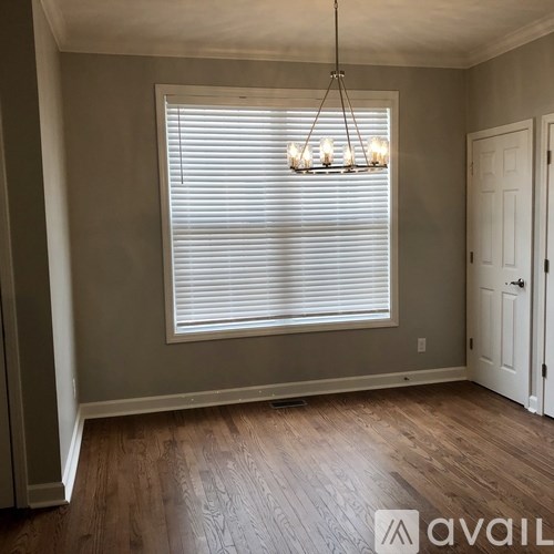 A room with wooden floors and a chandelier hanging from the ceiling.