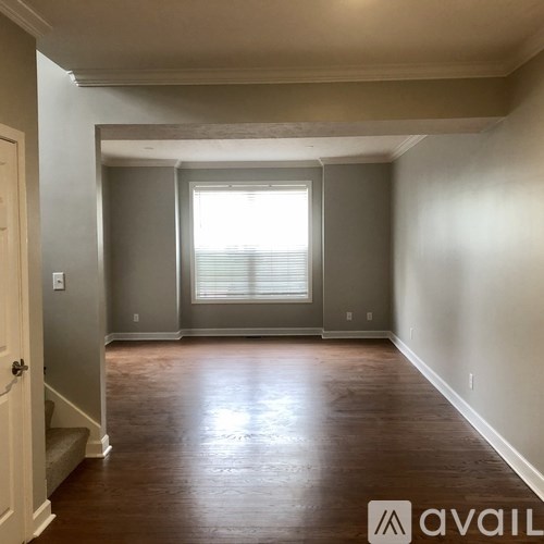 A room with wooden floors and a window with blinds.