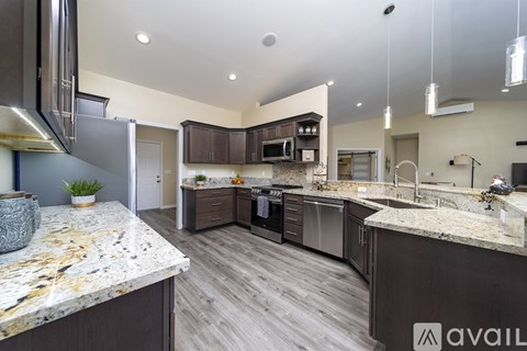 A kitchen with a marble countertop and wooden cabinets.