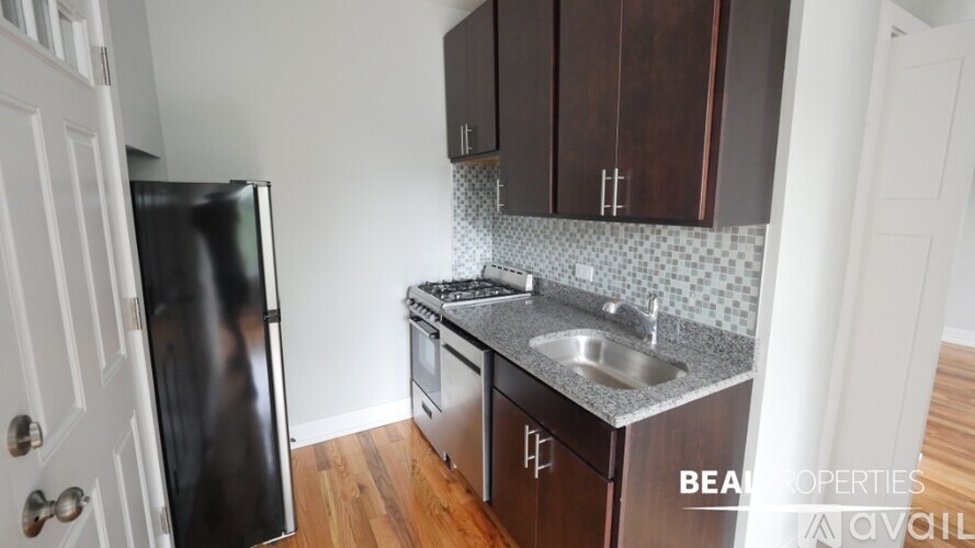 A kitchen with a black fridge, stove and wooden cabinets.