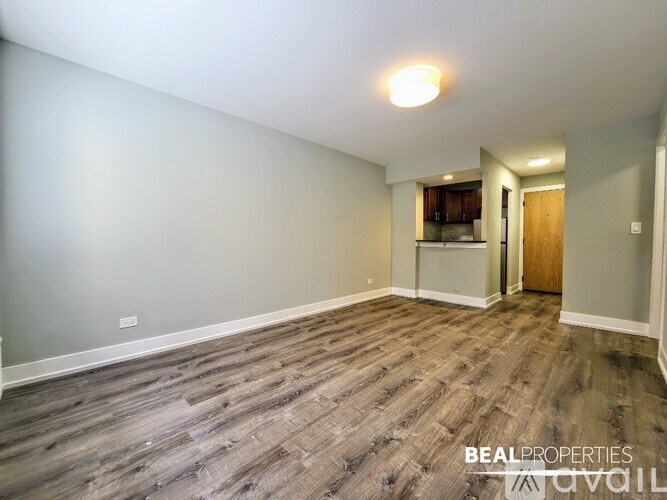 A room with wooden flooring and a door leading to another room.