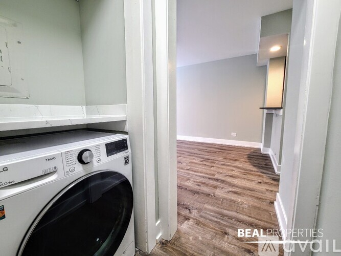 A white dryer is sitting in a laundry room with wood flooring.