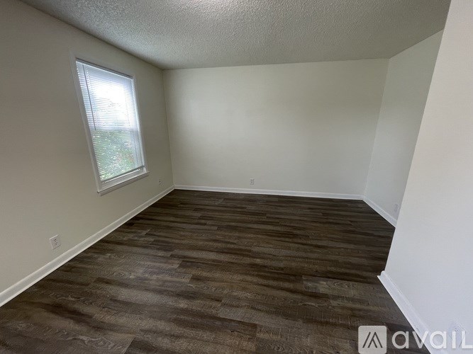 A room with a window and wooden flooring is available for rent.