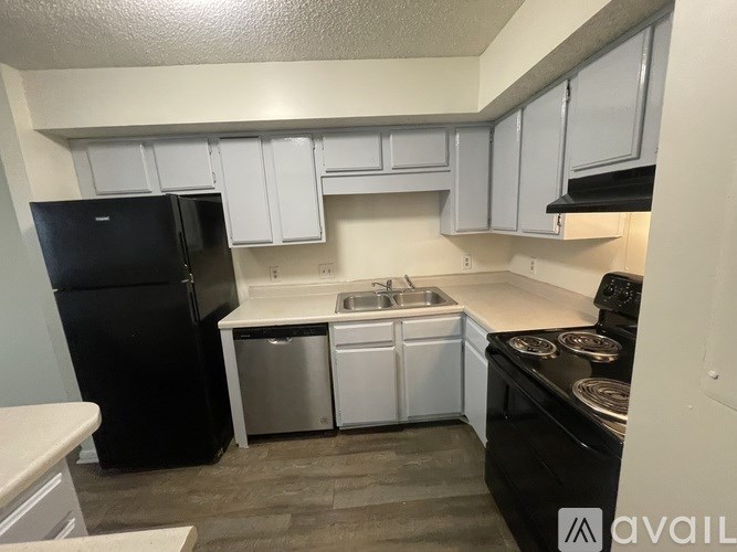 A kitchen with black appliances and white cabinets.