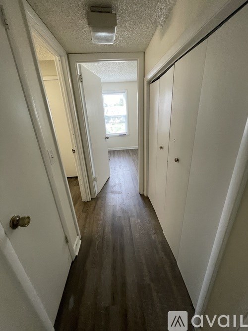 A long hallway with white walls and wood flooring.