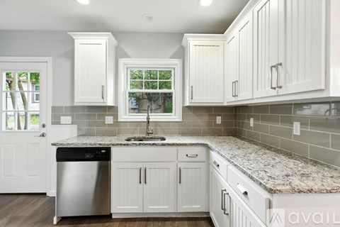 A kitchen with white cabinets and a granite countertop.
